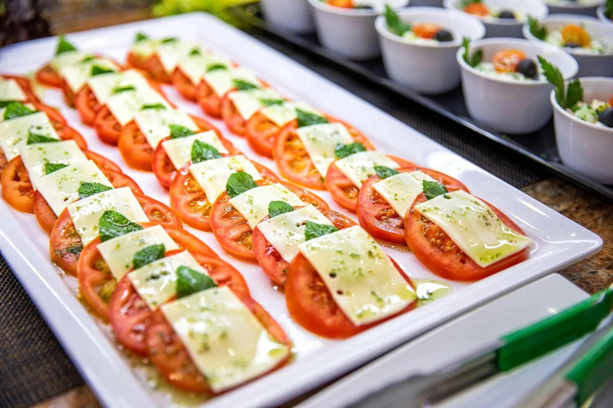 Présentation de tranches de tomates et de mozzarella décorées de basilic frais.