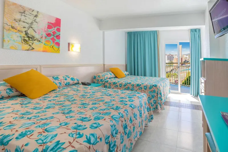 Chambre lumineuse avec deux lits simples et vue sur la mer.