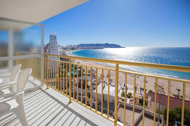 Vue sur la mer depuis un balcon avec des chaises longues.