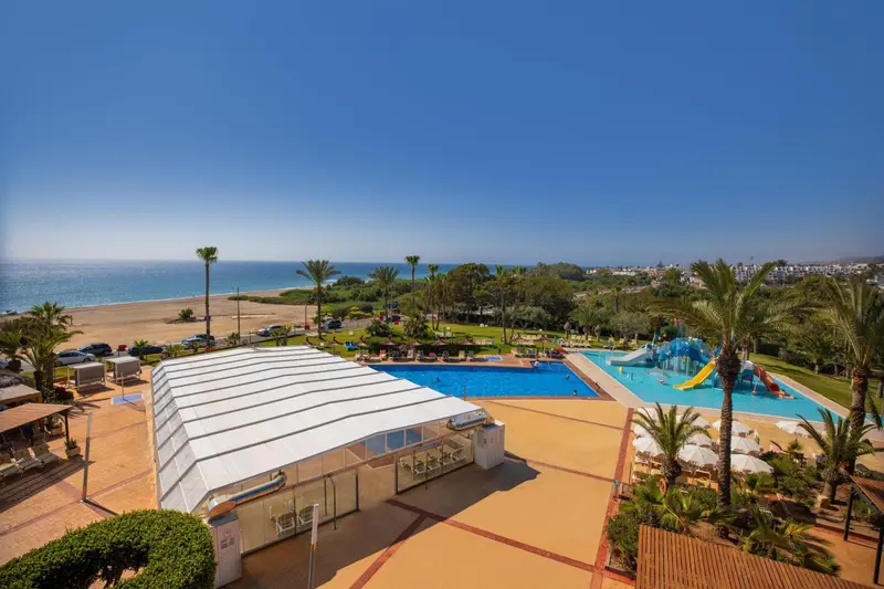 Vue aérienne d'un complexe hôtelier avec piscine et accès à la plage.
