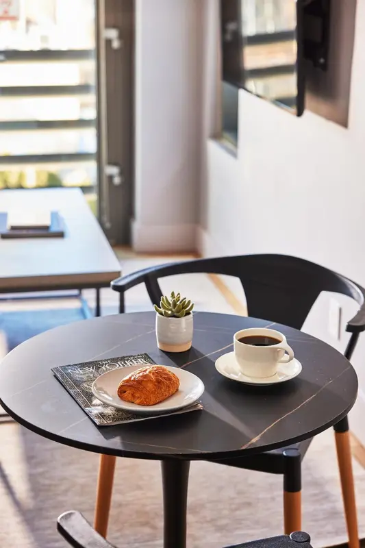 Une table ronde avec une tasse de café et une viennoiserie.