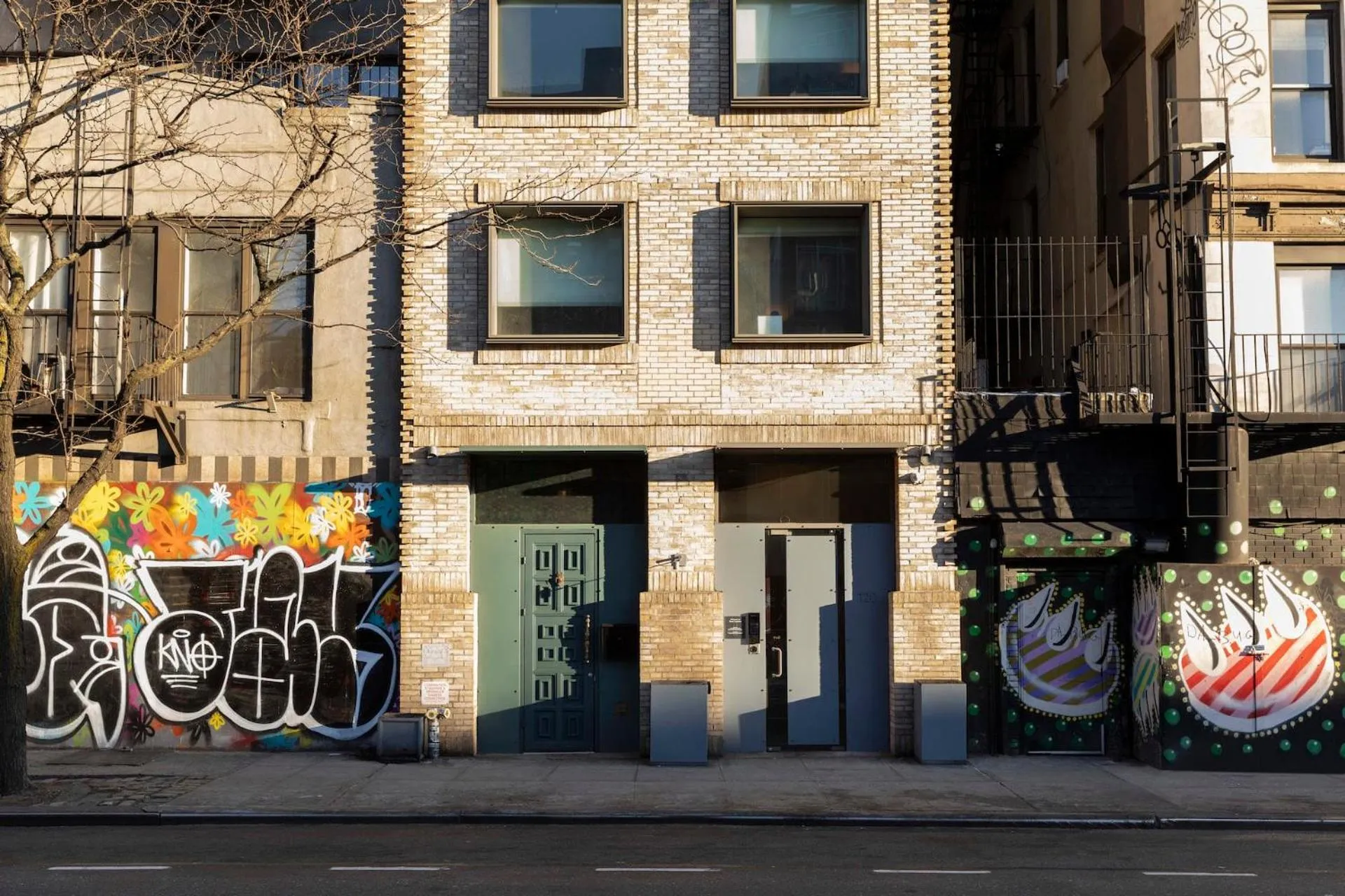 Façade d'un bâtiment urbain avec des graffitis et des portes grises.