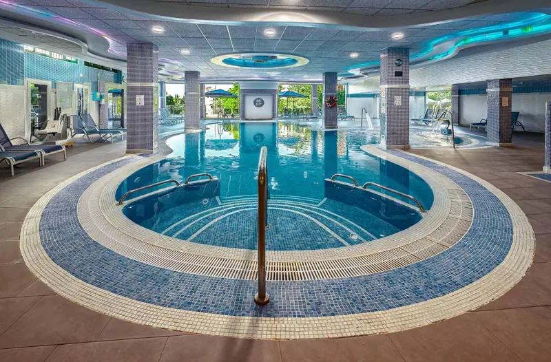 Une piscine intérieure avec un espace hydromassant et des chaises longues.