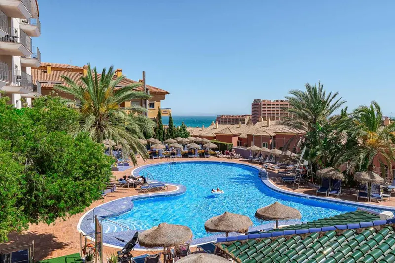 Piscine d'hôtel avec transats et parasols au milieu d'une végétation luxuriante.