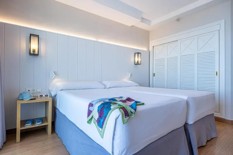 Une chambre lumineuse avec un grand lit et des meubles blancs.