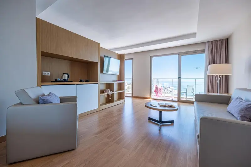 Espace de vie lumineux avec canapé, télévision et accès à une terrasse ensoleillée.