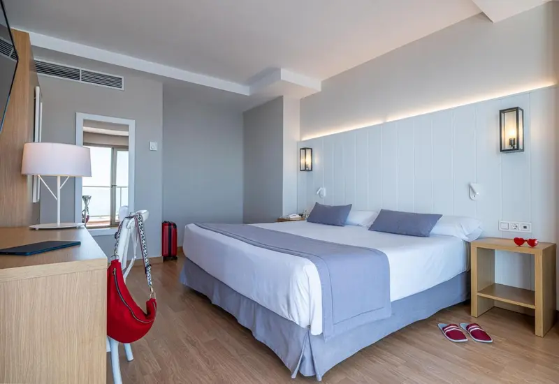 Une chambre lumineuse avec un grand lit et un bureau.