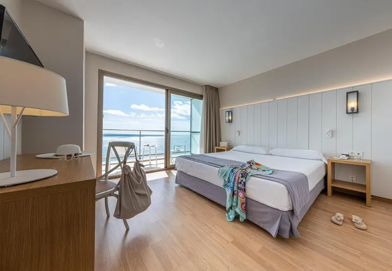 Une chambre lumineuse avec un lit double et un accès à un balcon.