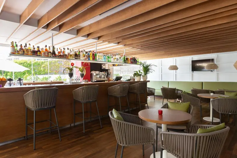 Un bar lumineux avec des tabourets et des tables.