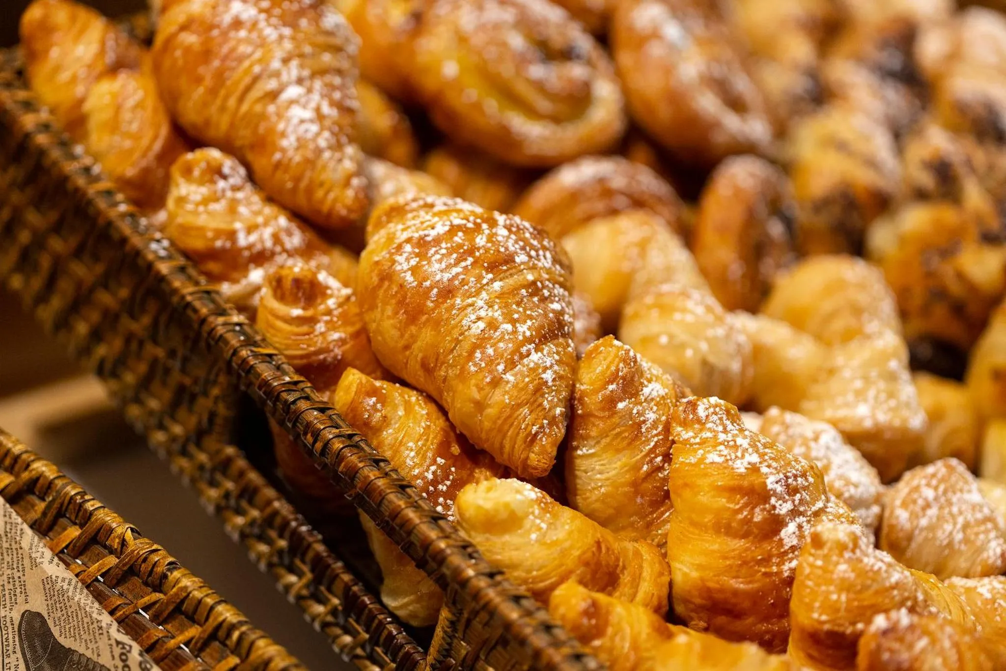 Une corbeille déborde de viennoiseries dorées et saupoudrées de sucre glace.