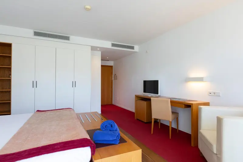 Chambre moderne avec un lit recouvert d'une courtepointe rouge et un espace bureau.