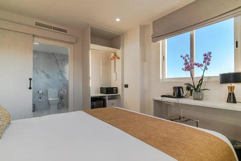 Une chambre lumineuse avec un lit et un bureau près d'une fenêtre.