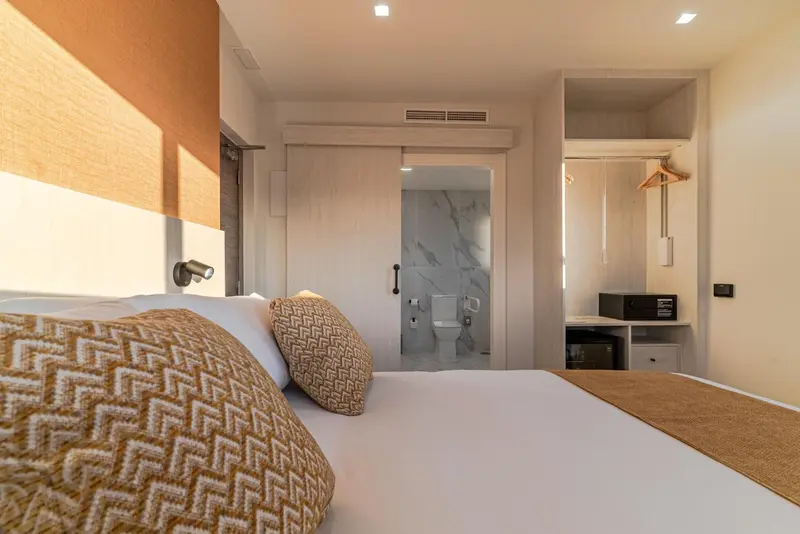 Une chambre lumineuse avec un lit fait et une salle de bain visible.