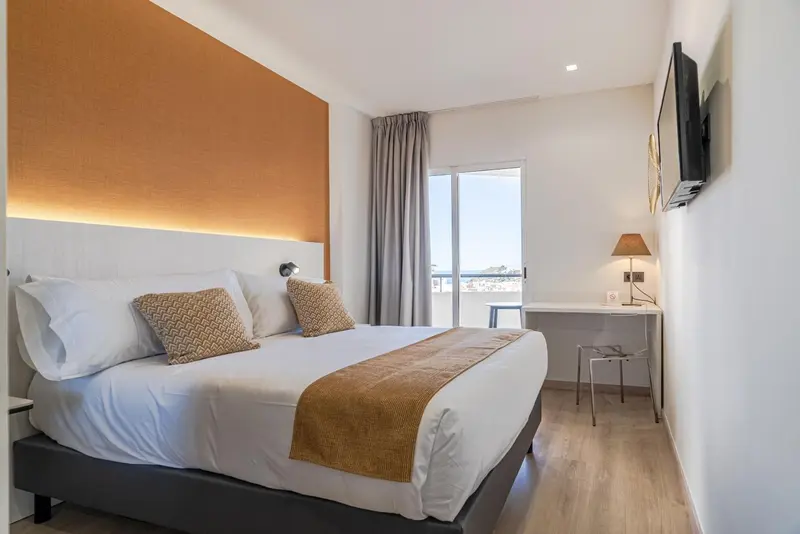 Une chambre lumineuse avec un grand lit et un bureau.