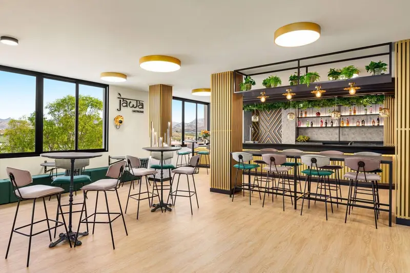 Une salle lumineuse avec un comptoir de bar et des tables hautes.