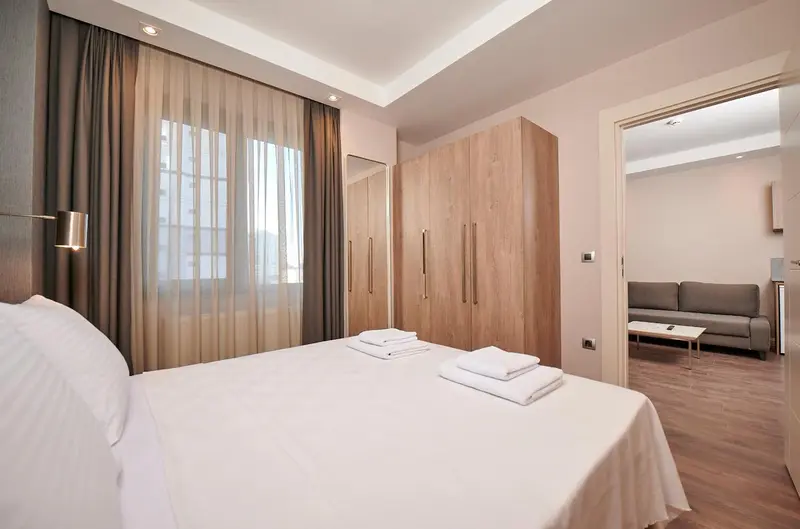 Une chambre lumineuse avec un grand lit et un accès à un espace salon.