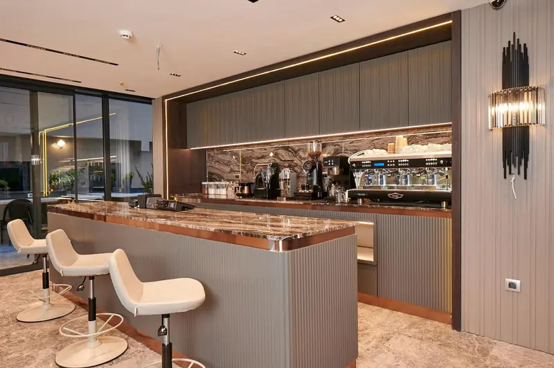 Un comptoir de bar moderne avec des tabourets blancs et un éclairage chaleureux.