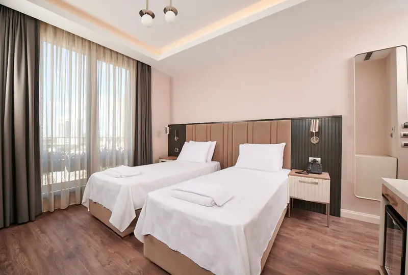 Une chambre lumineuse avec deux lits simples et un grand miroir.