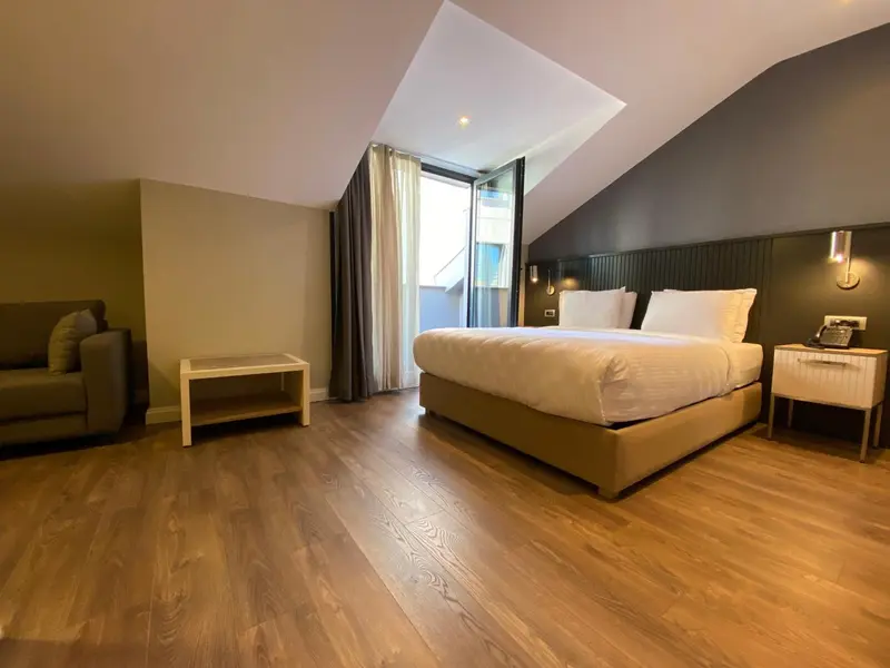 Une chambre lumineuse avec un lit double et un coin salon.
