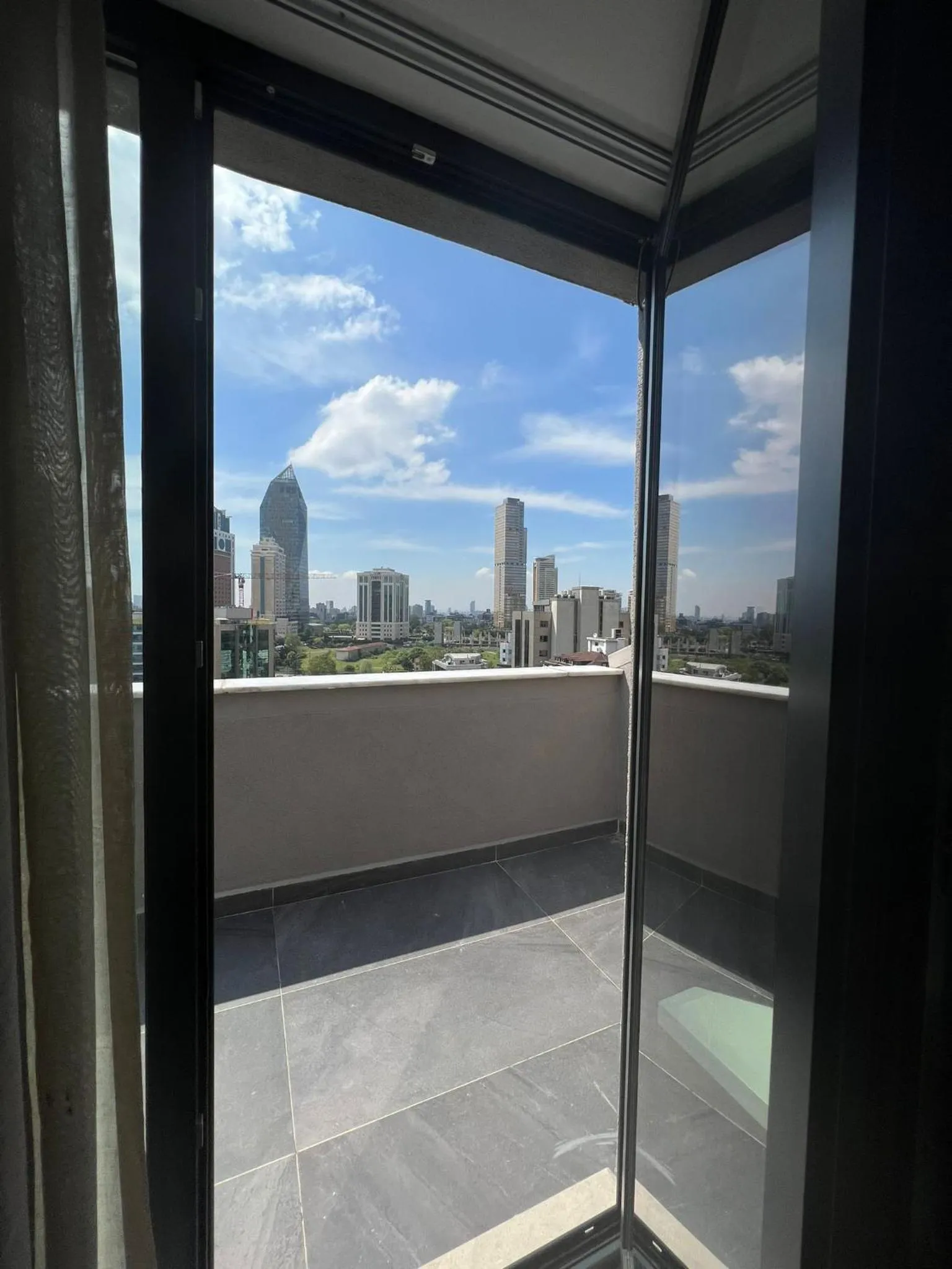 Vue sur la ville depuis un balcon avec garde-corps en verre.