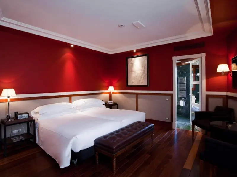 Une chambre à coucher lumineuse avec un grand lit et une décoration rouge et bois.