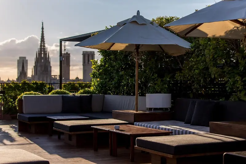 Terrasse aménagée avec des canapés et des tables basses offrant une vue sur une ville.