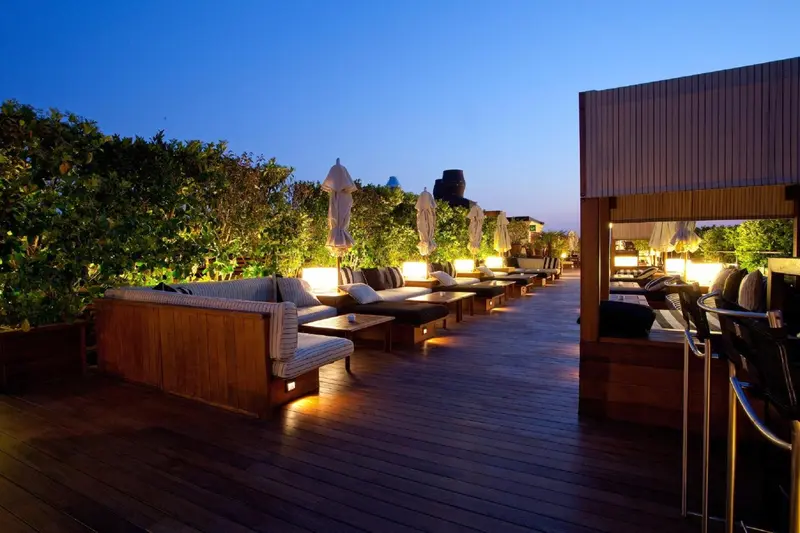 Terrasse aménagée avec des salons et des transats éclairés.