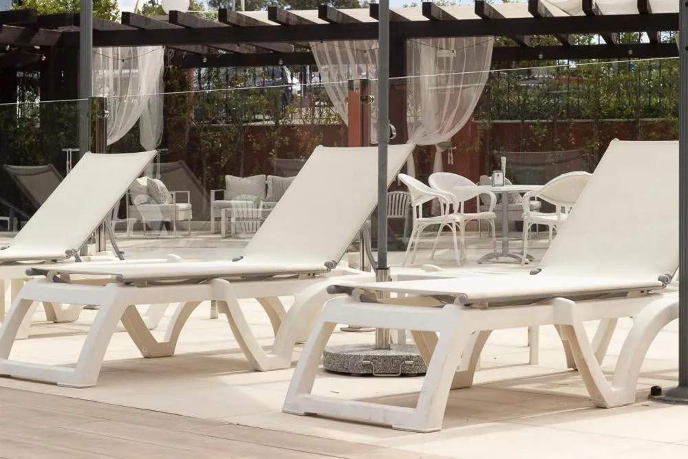 Transats blancs disposés sur une terrasse ombragée avec des rideaux.