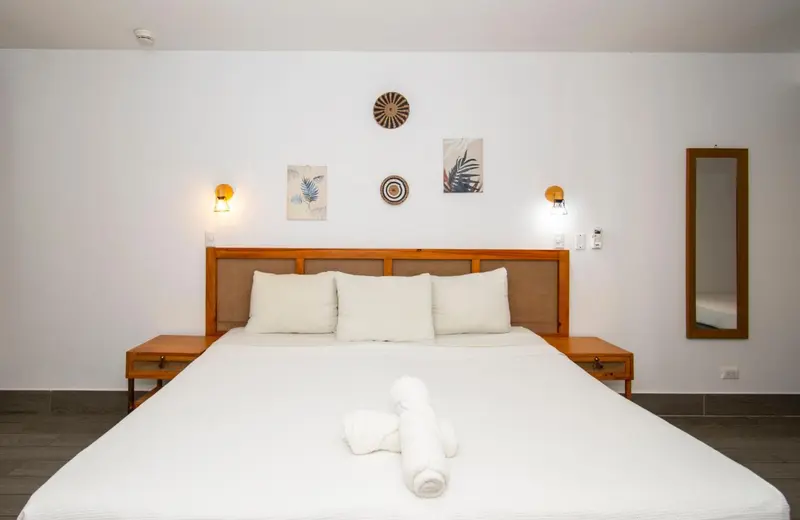 Un grand lit blanc avec des oreillers et une couverture dans une chambre lumineuse.
