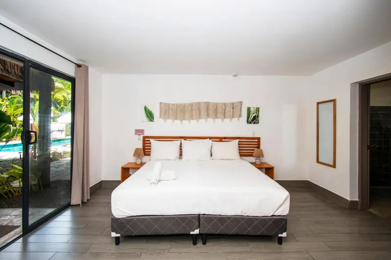 Une chambre lumineuse avec un grand lit et un accès à une terrasse.