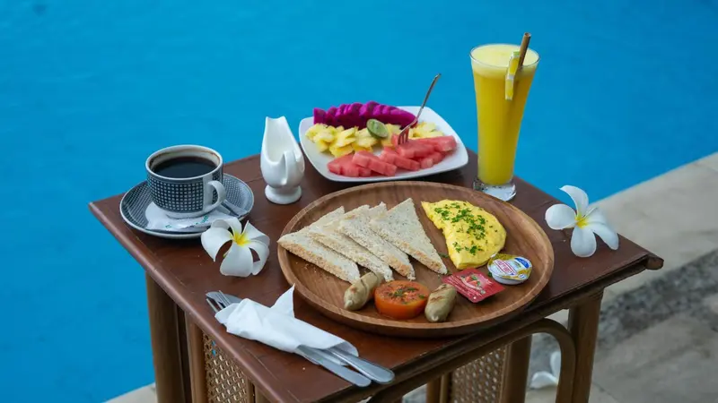 Un petit-déjeuner est servi sur une table basse au bord d'une piscine.