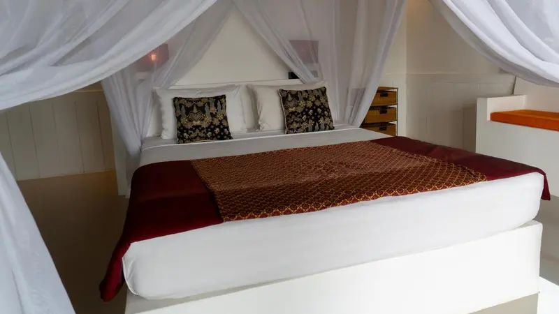 Un lit recouvert de textiles colorés dans une chambre lumineuse.
