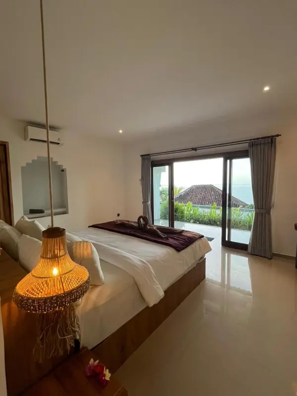 Une chambre lumineuse avec un grand lit et une vue sur la végétation.