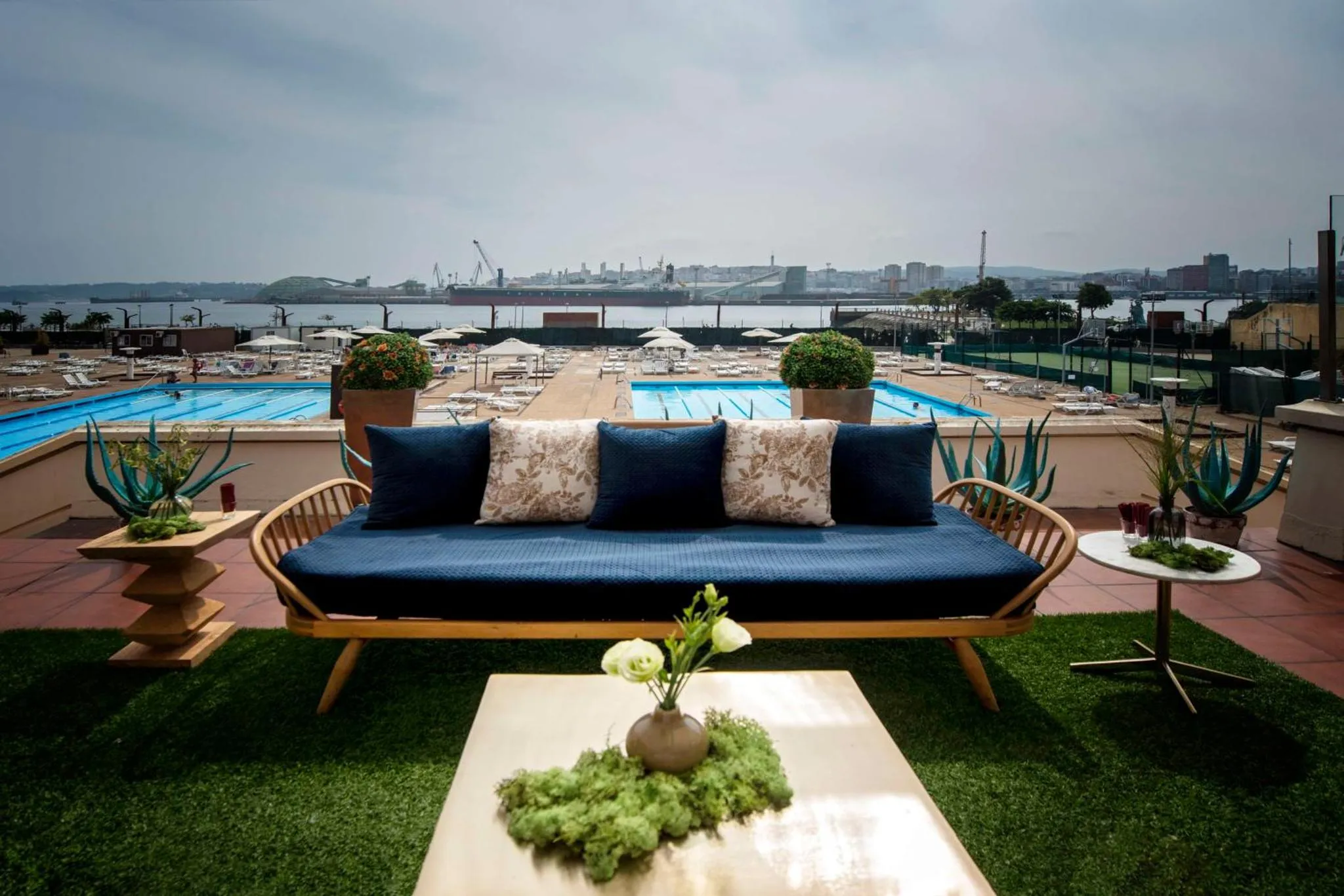 Espace de détente extérieur avec canapé et piscine face à la mer.