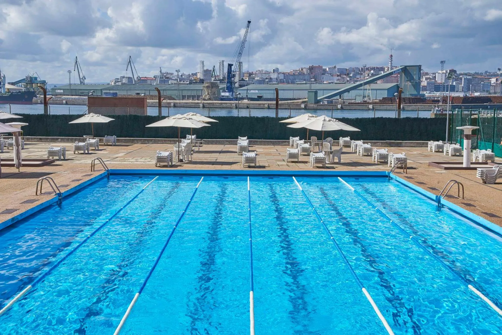 Une piscine rectangulaire avec des transats et des parasols sur une terrasse.