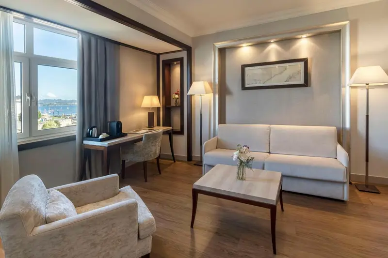 Un salon lumineux avec canapé et bureau près d'une fenêtre.