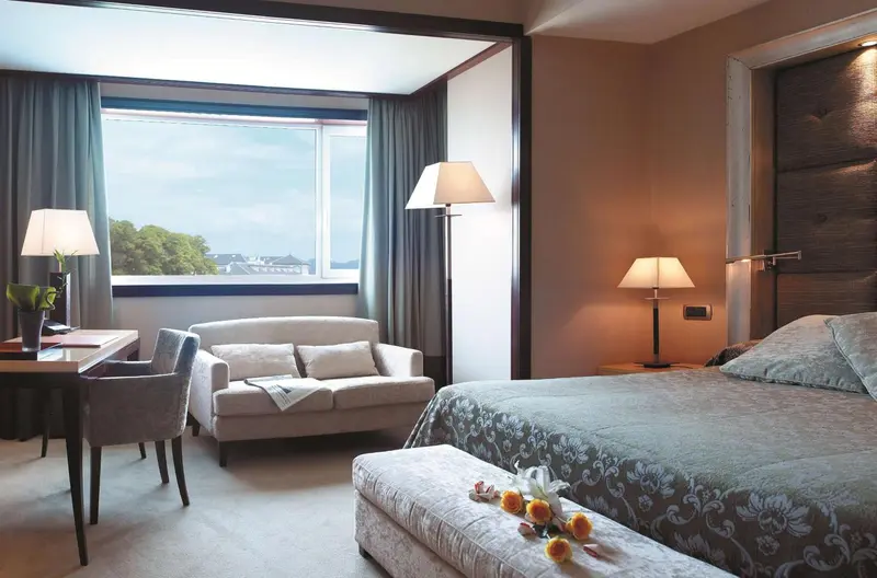 Une chambre lumineuse avec un canapé et un lit recouvert d'une courtepointe.