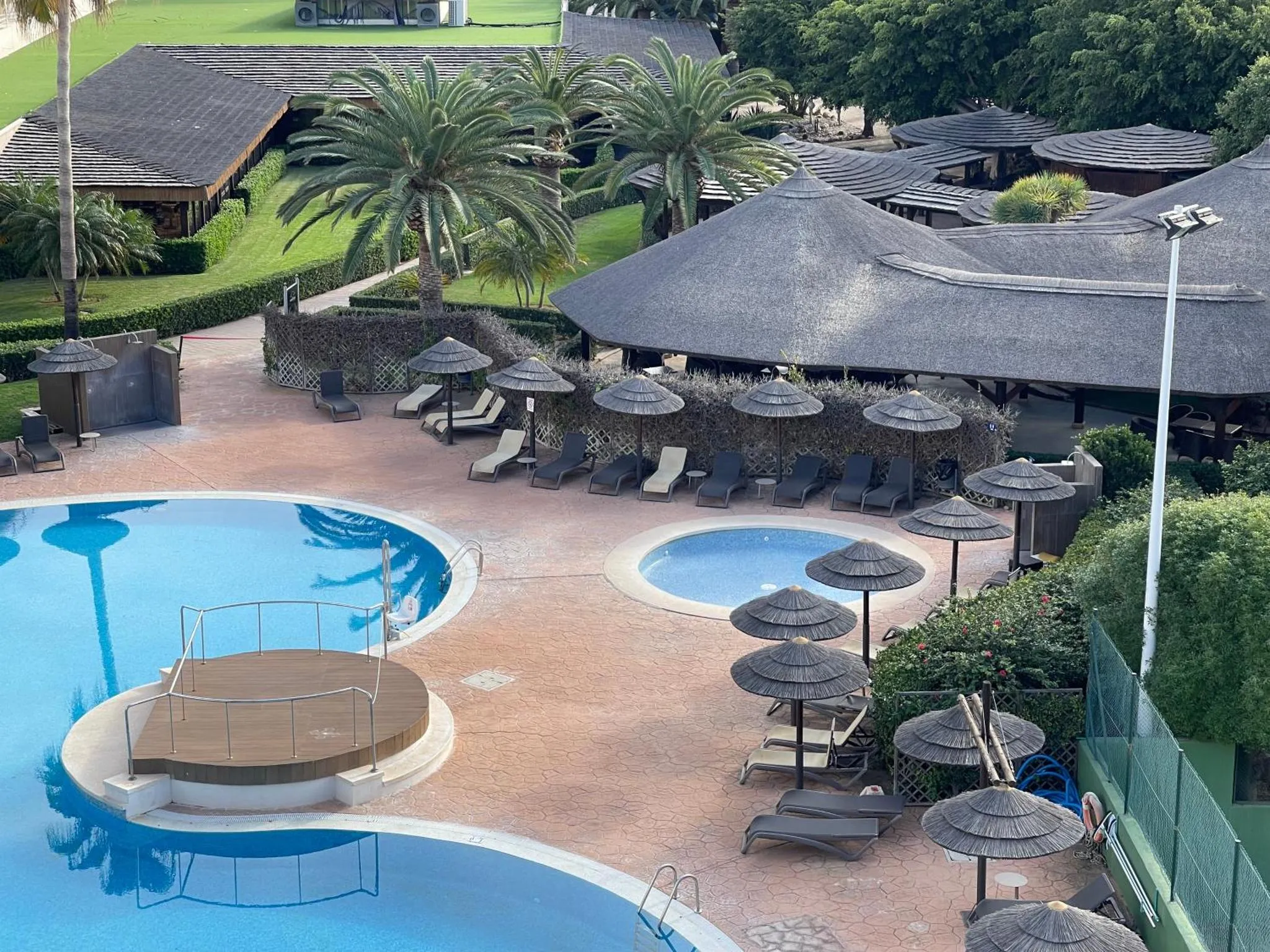Piscine avec transats et parasols au sein d'un complexe hôtelier.