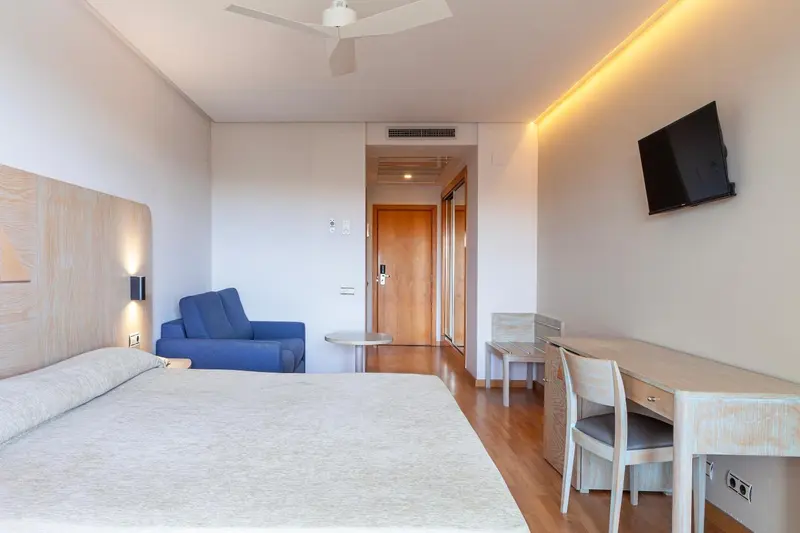 Une chambre lumineuse avec un lit, un canapé et un bureau.