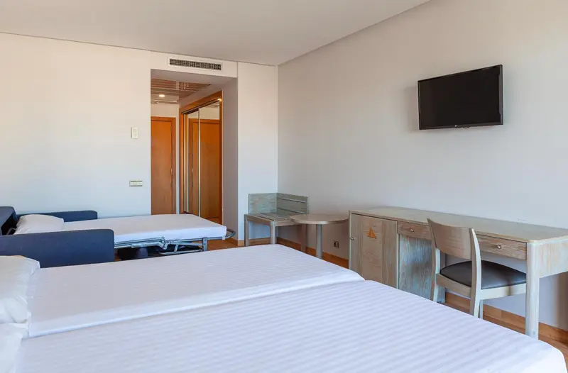 Une chambre d'hôtel lumineuse avec deux lits simples et un bureau.