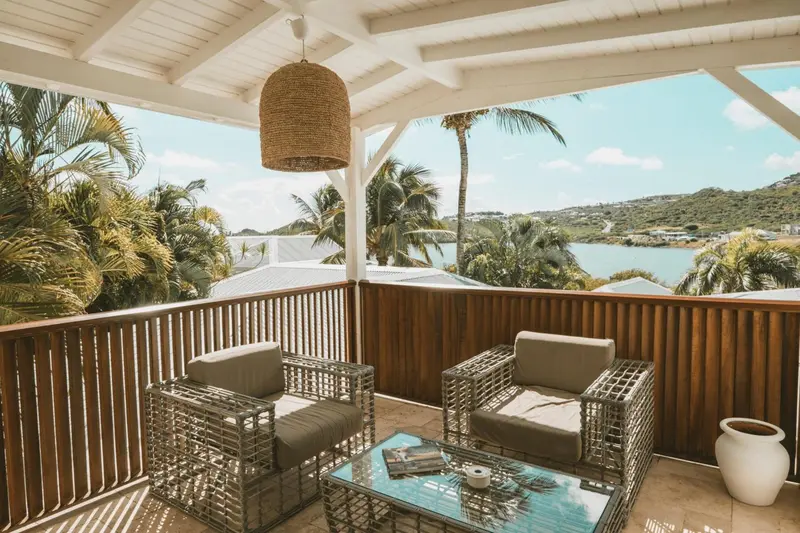 Terrasse aménagée avec mobilier de jardin et vue sur la végétation et la mer.