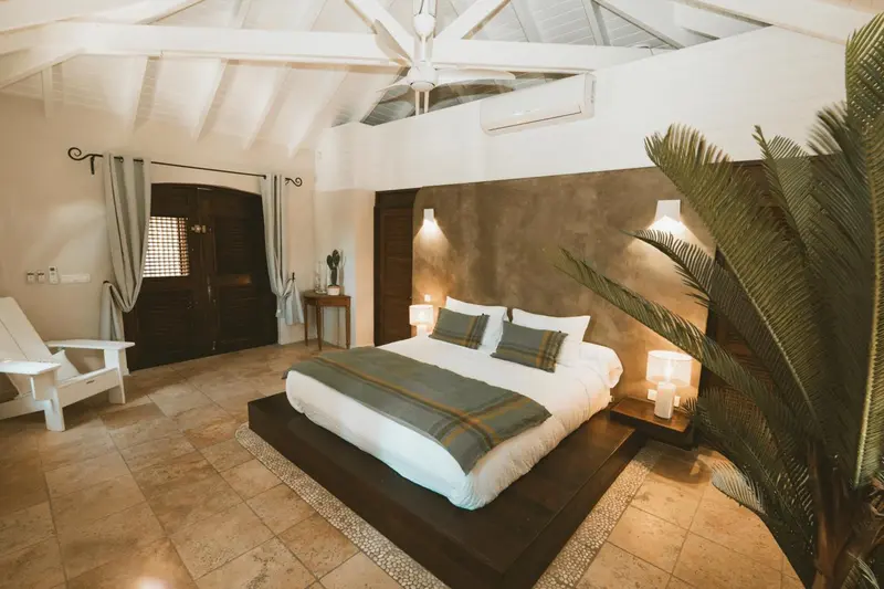Une chambre lumineuse avec un grand lit et une décoration tropicale.
