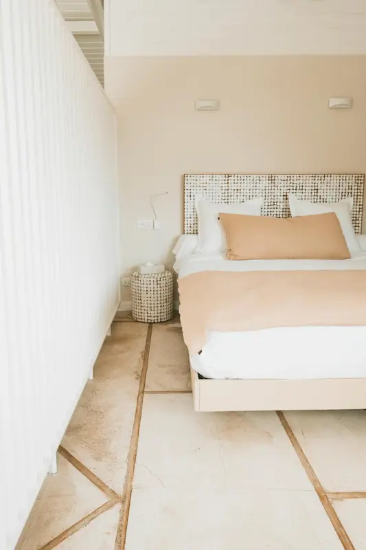 Une chambre lumineuse avec un lit recouvert d'une courtepointe rose et de coussins.