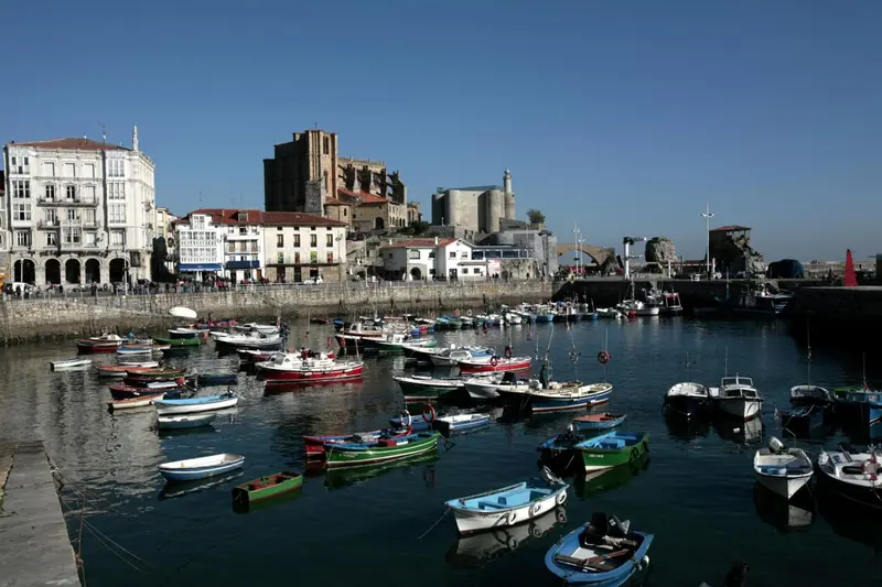 Port de plaisance avec des bateaux amarrés devant une ville côtière.