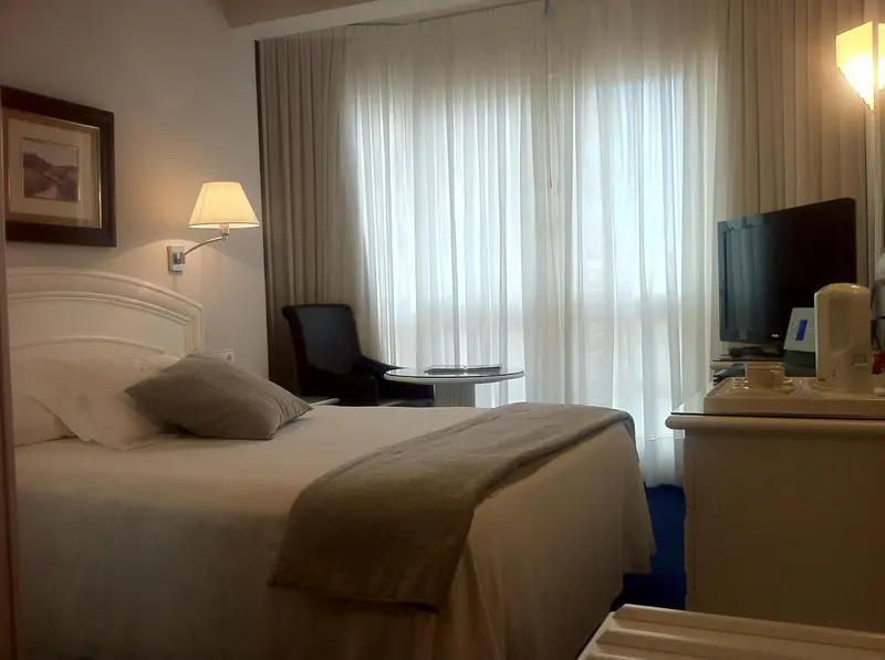 Une chambre lumineuse avec un grand lit et une fenêtre drapée.