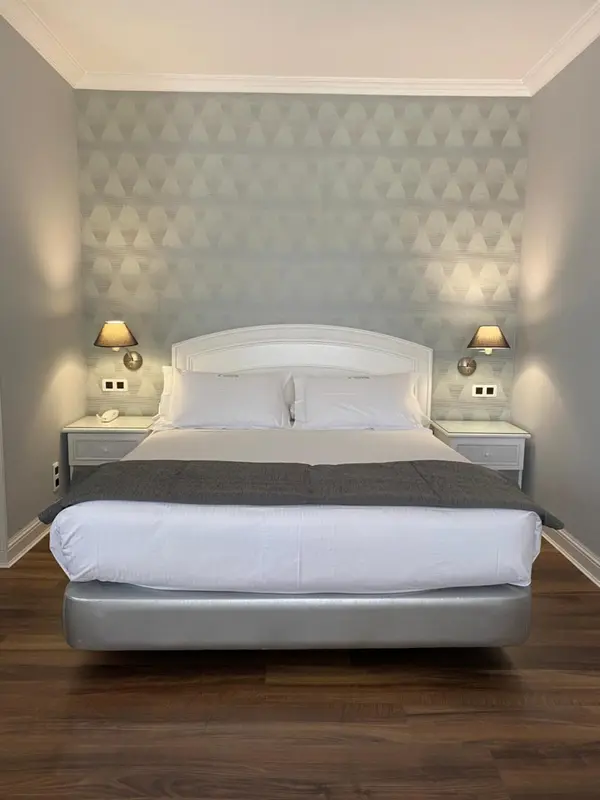 Une chambre avec un grand lit recouvert d'une couette blanche et de coussins.