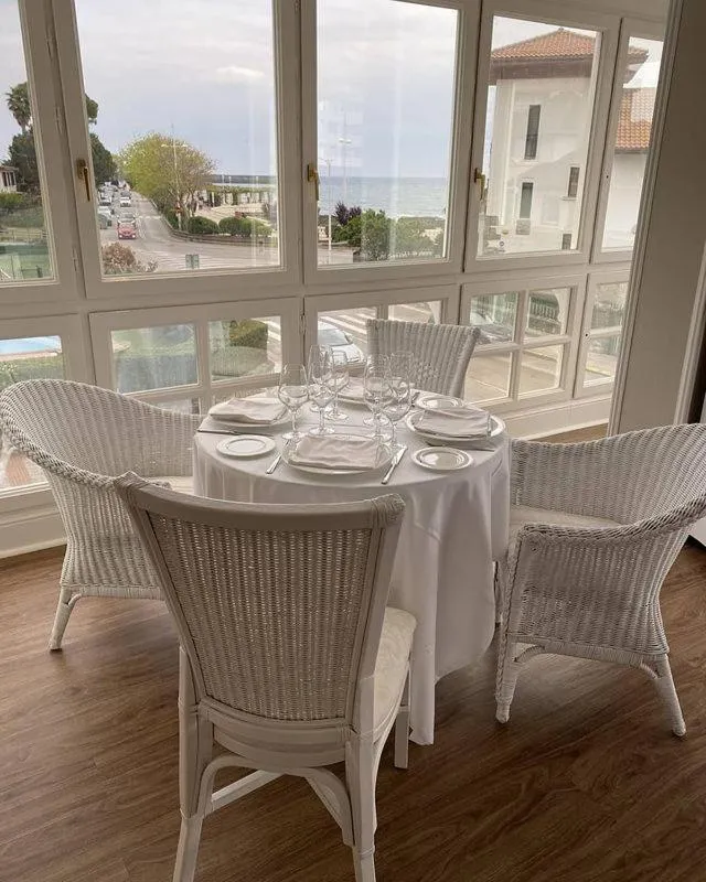 Une table est dressée devant une grande baie vitrée donnant sur la mer.