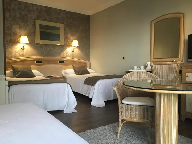 Une chambre lumineuse avec deux lits et un coin repas.