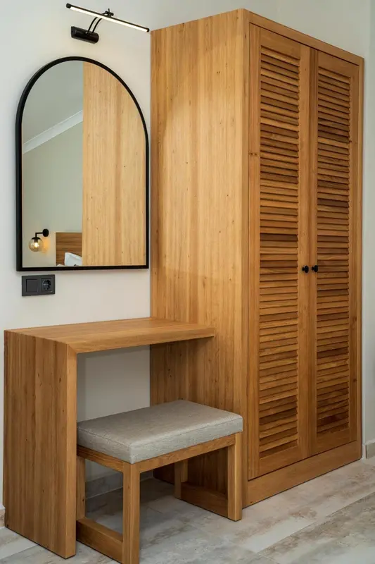 Un coin coiffeuse avec un miroir et un meuble en bois clair.