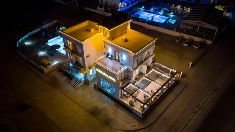 Bâtiment illuminé avec des terrasses et une piscine la nuit.